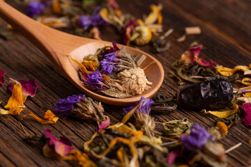 Obraz na płótnie Canvas Healing tea made from dried flowers in a wooden spoon close-up. Dried flower petals close-up. Healing tea made from dried flowers. Dried tea petals from flowers close-up.