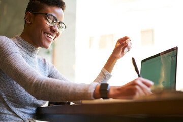 Happy African American female freelancer in cafe