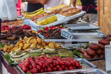 Healthy street food to go - sausages, poultry, meat, bell peppers and red tomatoes. Delicious food cooked over an open fire, which is offered at a street food fair, event, festival.