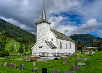 Fototapeta na wymiar Urlaub in Süd-Norwegen: Schöne weiße Kirche und Friedhof Viksdalen Kirke in Vik