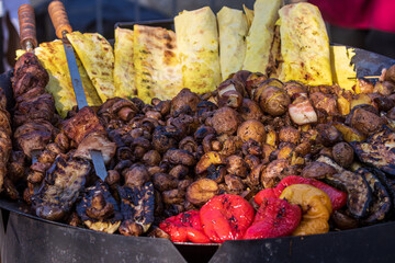 Healthy street food to go - sausages, poultry, meat, bell peppers and red tomatoes. Delicious food cooked over an open fire, which is offered at a street food fair, event, festival.