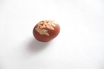 Painted Easter egg on a white background. Floral pattern on a red eggshell. Festive food.