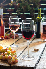 Glasses with red and rose wine, outdoor recreation, wooden table with glasses of wine, bottles of wine and grapes