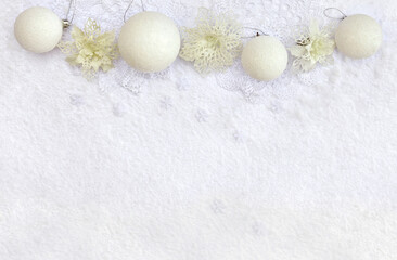 Fototapeta na wymiar Christmas decoration. White christmas balls, white openwork flowers, snowflakes on snow with space for text. Top view, flat lay