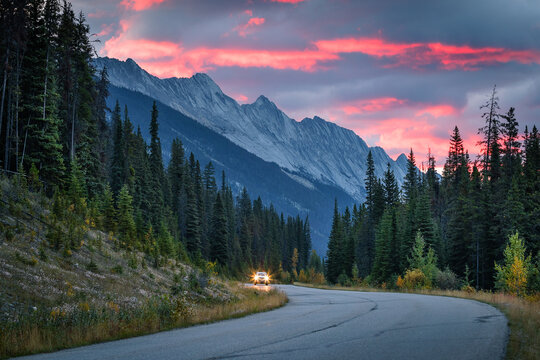 A vehicle on the curved roads of the Canadian rockies in the early morning with red and blue coloured skies (Jasper, Alberta, Canada)