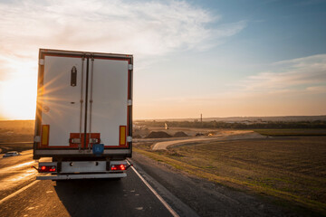 Sunset on the motorway and a truck shot from the passenger seat through a dirty windscreen, blurred focus through t