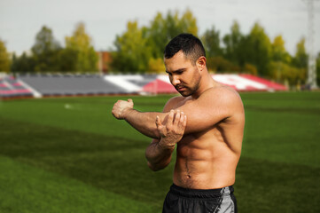 A young strong man trains at the stadium. Warm-up before training. Outdoor sports activities....