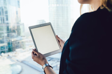 Cropped back view of female with modern digital tablet with copy space area for internet advertising, selective focus on hands holding mockup touch pad with blank screen for your web publication