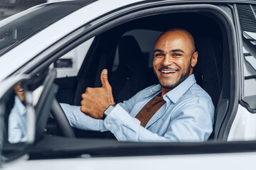 Portrait of a handsome happy African American man sitting in his newly bought car