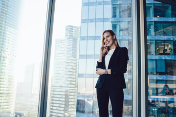 Fototapeta premium Smiling businesswoman touching chin near window in office