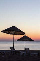 wicker umbrellas on the beach at sunrise