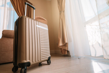 Travel suitcase stands in a white clean hotel room with light from the window, relaxing time, holiday, weekend and traveling concept.