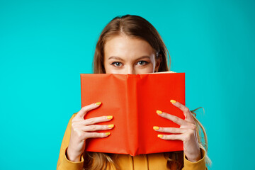 Young woman student hiding her face behind the book