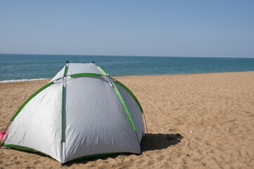 Fototapeta premium A lone green tourist tent stands on the seashore. 