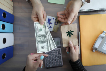 Closeup of burning packet of marijuana for cash dollars. Illegal drug distribution concept.