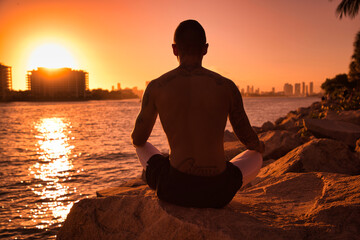 Man practicing yoga on the beach during sunrise/sunset