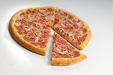 Pepperoni pizza slice with onin rings on white background. Copy space. Selective focus