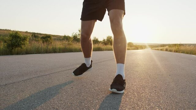 Low view of kickboxer's legs during training kicks on country road singly