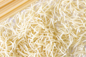 Uncooked italian pasta as background texture close up. Small layer of dry noodles. The food background is a pasta texture. Homemade noodles. Cooking. Background. Texture. View from above. Cooking. 