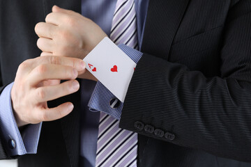 Man in suit puts ace of chirv card into sleeve of his jacket. Decisive secret business idea concept.