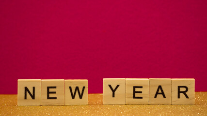 Words  new year are written on wodden blocks  on pink and gold background. Card. Banner. 2021