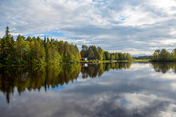 Obraz premium Beautiful landscape in Finland at the lake shore. Reflecting waters and cloudy sky. Calm scenery for poster and wallpaper use.