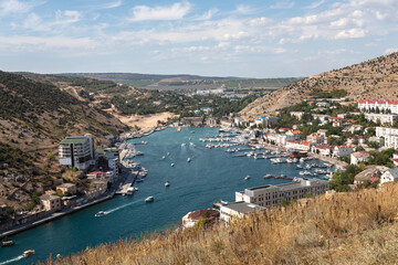 Picturesque panoramic view of Balaclava bay with yachts and green hills opens from the ruins of Genoese fortress Chembalo. Balaklava, Sevastopol, Crimea.
