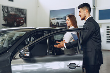 Man car dealer showing a woman buyer a new car