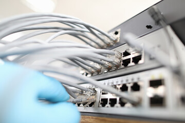 Technician checks the quality of internet connection against background cable hub close-up. Computer bad network cabling concept