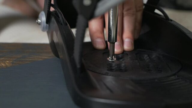 The man's hand attaches the bindings to the snowboard. Prepares the snowboard for winter