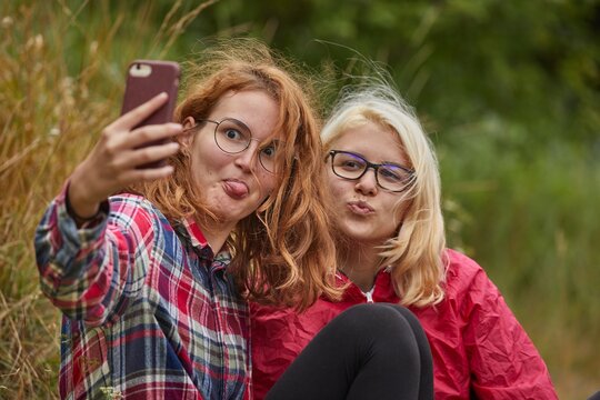Girls taking selfies with a smartphone outoors in natural environment on a hikin trip
