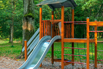 Wooden children playground with slide, ladder, bridge in the forest.