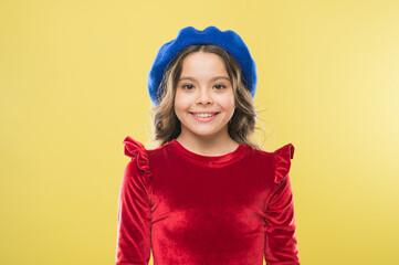 happy parisian girl in french beret hat and elegant red dress on yellow background, kid retro fashion