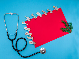 stethoscope and the inscription merry christmas on a red letterhead with a branch of a christmas...