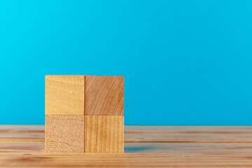 Stacked wooden blocks on wooden desk against blue background