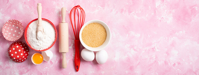 Baking background. Food ingredients for baking flour, eggs, sugar on pink background flat lay. Baking or cooking cakes or muffins. Long format with copy space. Top view