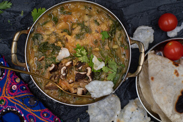 Indian spinach and lentil stew, saag dal, with flat breads on dark table