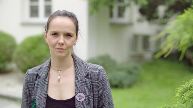 Young and serious woman standing in the garden.