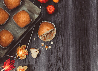 Obraz na płótnie Canvas pumpkin muffins on black background Pumpkin muffins in an iron baking sheet on the left on a black wooden table with space for text on the right, flat lay close-up.