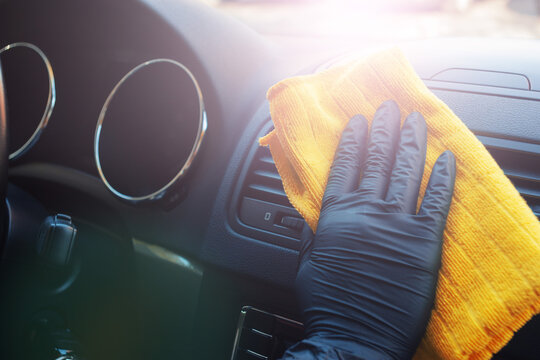 Cleaning car interior from coronovirus and pandemic with disinfectant fluid. Hands in rubber protective gloves wipe the car inside to protect against viral diseases