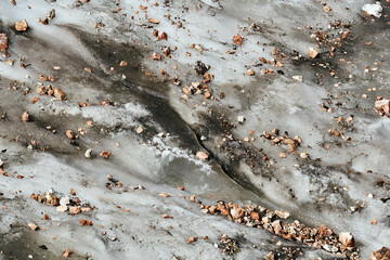 surface of a melting mountain glacier covered with stones and rubble