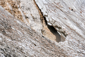 cleft in a melting mountain glacier with fog swirling over it