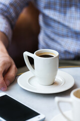 Businessman sitting in cafe, drinking morning coffee and using smartphone