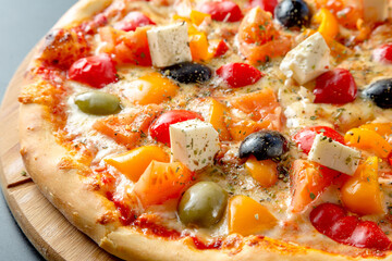 Greek pizza with olives, bell peppers, feta cheese and tomatoes.