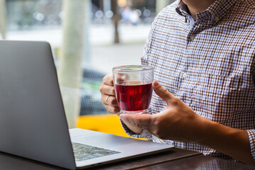 Businessman sitting in cafe, drinking healthy tea and using laptop