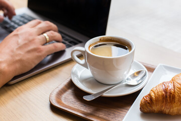 Freelancer sitting in cafe, drinking coffee and using a laptop