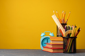 Office cup with pencils and stationery against yellow background