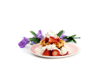 Belgian waffles with strawberries and whipped cream on a pink plate with blue flowers
