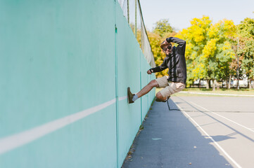 The guy is dancing against the blue wall.