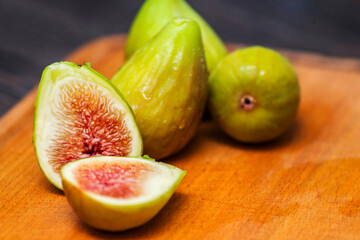 Ripe fresh figs on a cutting kitchen board on a rustic wooden table. Ripe tasty figs